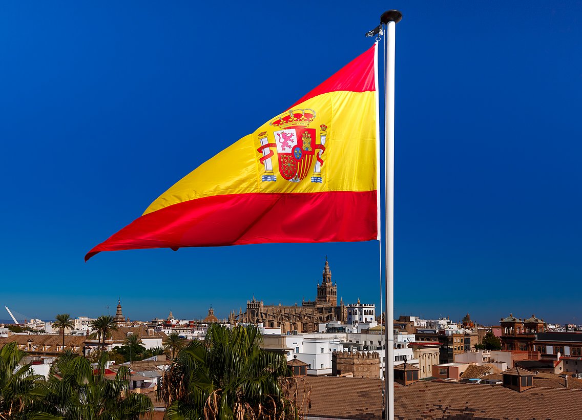 Bild einer Stadt hinter der spanischen Flagge