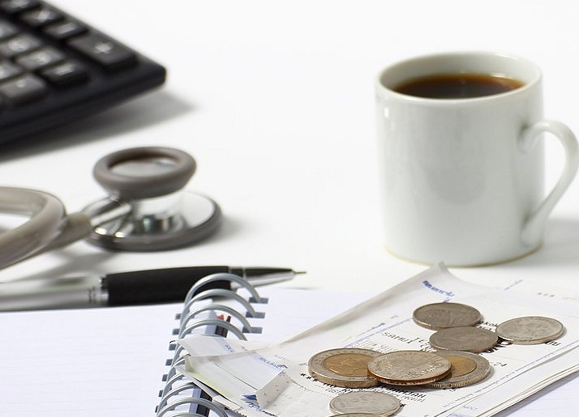 Stethoskop, Kaffeebecher und Münzen