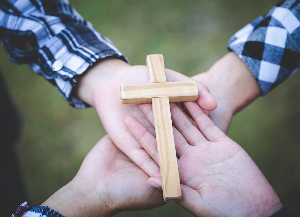 Bild eines Kreuzes auf Händen getragen