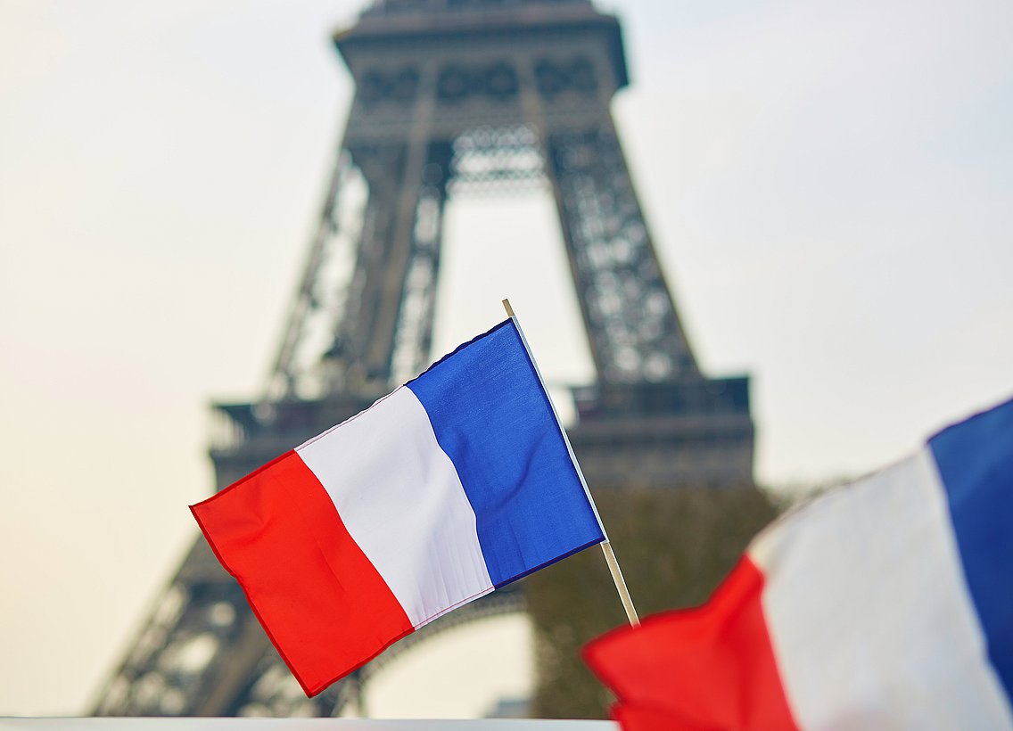 Bild vom Eiffelturm hinter der französischen Flagge